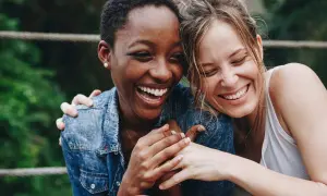 Zwei lachende Frauen, die sich umarmen. Ein Bild, das die psychologische Definition von Freundschaft perfekt einfängt: Vertrauen, Nähe und Freude.