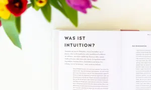 Blumen und ein Buch über Intuition. Lerne, deine Intuition zu trainieren und dem Bauchgefühl zu vertrauen.