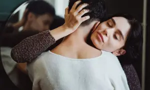 Frau umarmt ihren Partner, der sich abwendet. Sie sucht Nähe, wenn sie sich depressiv fühlt. Was tun?