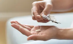 Eine Hand hält eine Tablette aus einer Blisterpackung, während eine andere Hand eine einzelne Tablette auffängt. Mögliche pregabalin nebenwirkungen im Blick.