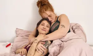 Zwei Frauen kuscheln im Bett. Ihre Nähe und Zärtlichkeit zeigen die wahre Bedeutung von Sexappeal: tiefe Verbundenheit und Intimität.