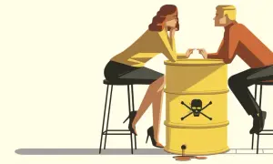 Ein Mann und eine Frau sitzen sich gegenüber, getrennt durch einen gelben Fass mit Totenkopf-Symbol. Die Szene symbolisiert Manipulation in der Beziehung, wo giftige Gefühle die Verbindung vergiften.