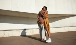 Ein Paar umarmt sich innig vor einer Betonwand. Ihre Körperhaltung strahlt tiefe **liebe und vertrauen** aus, ein Moment der Verbundenheit im hellen Sonnenlicht.
