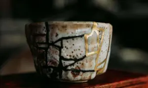 Zerbrochene Keramik, repariert mit Gold, symbolisiert die Kintsugi Psychologie: Narben machen uns stärker und schöner.