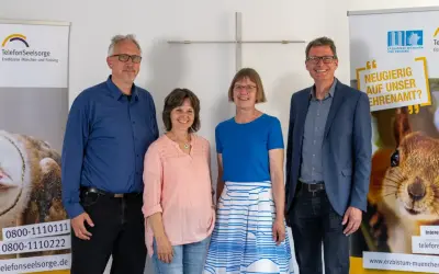 Vier Personen stehen vor Bannern der Telefonseelsorge. Sie werben für ehrenamtliche Tätigkeiten als telefonseelsorge alternative.