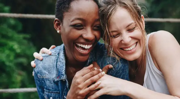 Zwei lachende Frauen, die sich umarmen. Ein Bild, das die psychologische Definition von Freundschaft perfekt einfängt: Vertrauen, Nähe und Freude.
