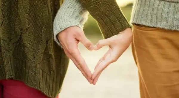 Zwei Hände formen ein Herz, ein Symbol für eine tiefe Partnerbeziehung.