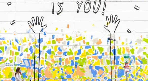 Bunte Wandmalerei mit der Botschaft "The best gift is you!". Eine Frau schiebt einen Kinderwagen. Dies erinnert an die psychologischen werte tests, die uns lehren, uns selbst wertzuschätzen.