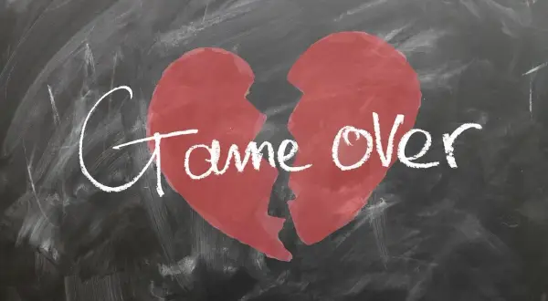 Ein zerbrochenes Herz auf einer Tafel mit der Aufschrift "Game Over". Ein Symbol für den tiefen Schmerz und die Trauer nach einer Trennung.