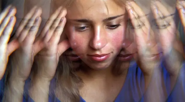 Verzerrte Ansicht einer jungen Frau mit Händen an den Schläfen, die innere Zerrissenheit und psychotische Depression erfahrungsberichte widerspiegelt.