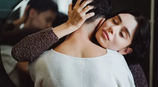Frau umarmt ihren Partner, der sich abwendet. Sie sucht Nähe, wenn sie sich depressiv fühlt. Was tun?