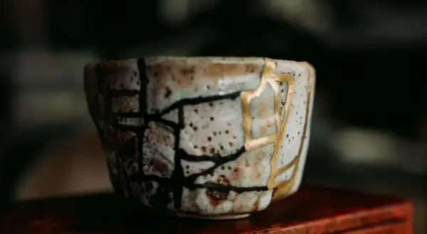 Zerbrochene Keramik, repariert mit Gold, symbolisiert die Kintsugi Psychologie: Narben machen uns stärker und schöner.