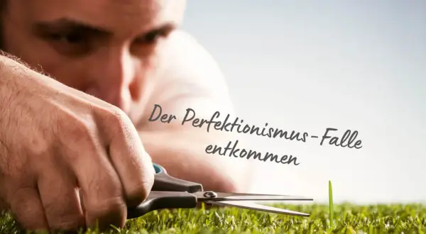 Mann schneidet mit Schere ein einzelnes Grashalm. Die Psychologie des Perfektionismus zeigt sich in diesem Detail.