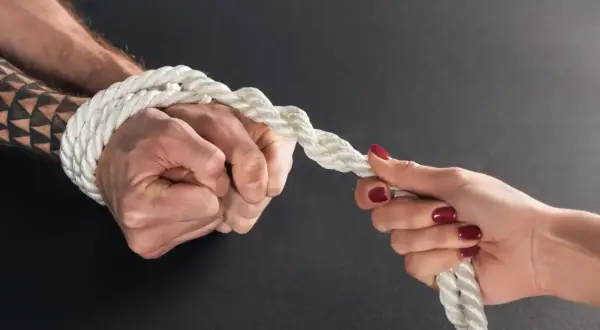 Zwei Hände ziehen an einem Seil. Eine Hand ist gefesselt, ein Test, ob man keine Liebe empfinden kann.
