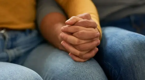 Zwei Hände halten sich fest. Die Frage, warum trennen sich depressive vom Partner, beschäftigt viele.