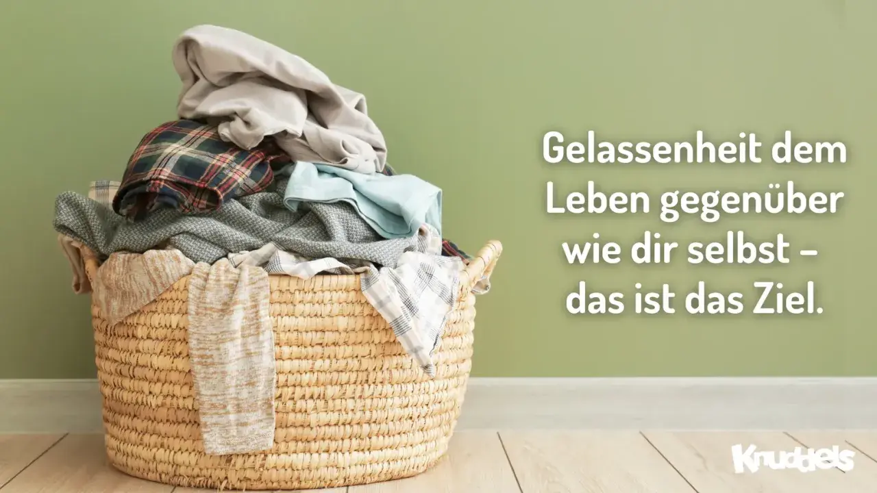 Ein Wäschekorb voller Kleidung vor einer grünen Wand. Der Spruch "Gelassenheit dem Leben gegenüber wie dir selbst – das ist das Ziel" lädt dazu ein, das eigene Bewusstsein zu erweitern.