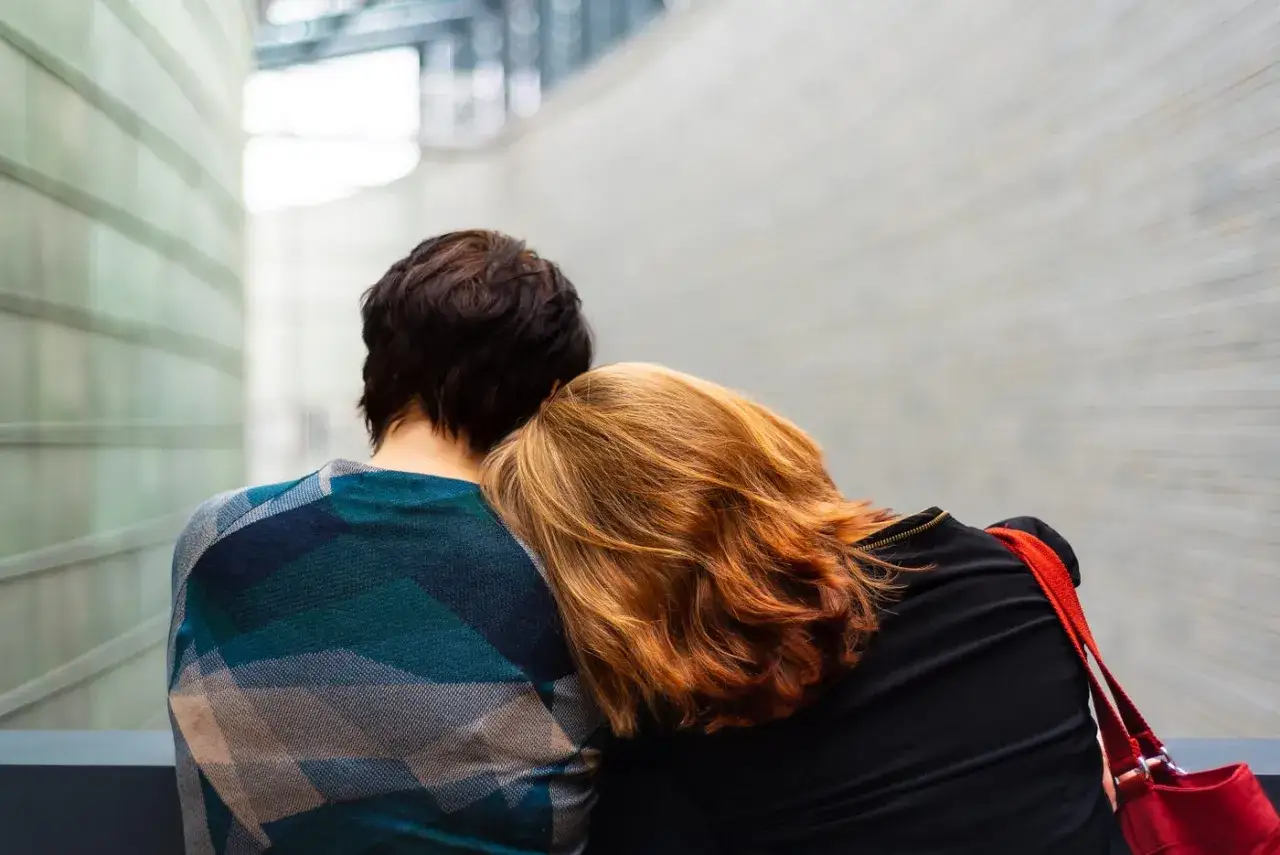 Zwei Frauen, eine mit dunklem Haar, die andere mit roten Haaren, die sich anlehnt. Wenn die Partnerin depressiv ist, was tun? Unterst&uuml;tzung und N&auml;he sind wichtig.