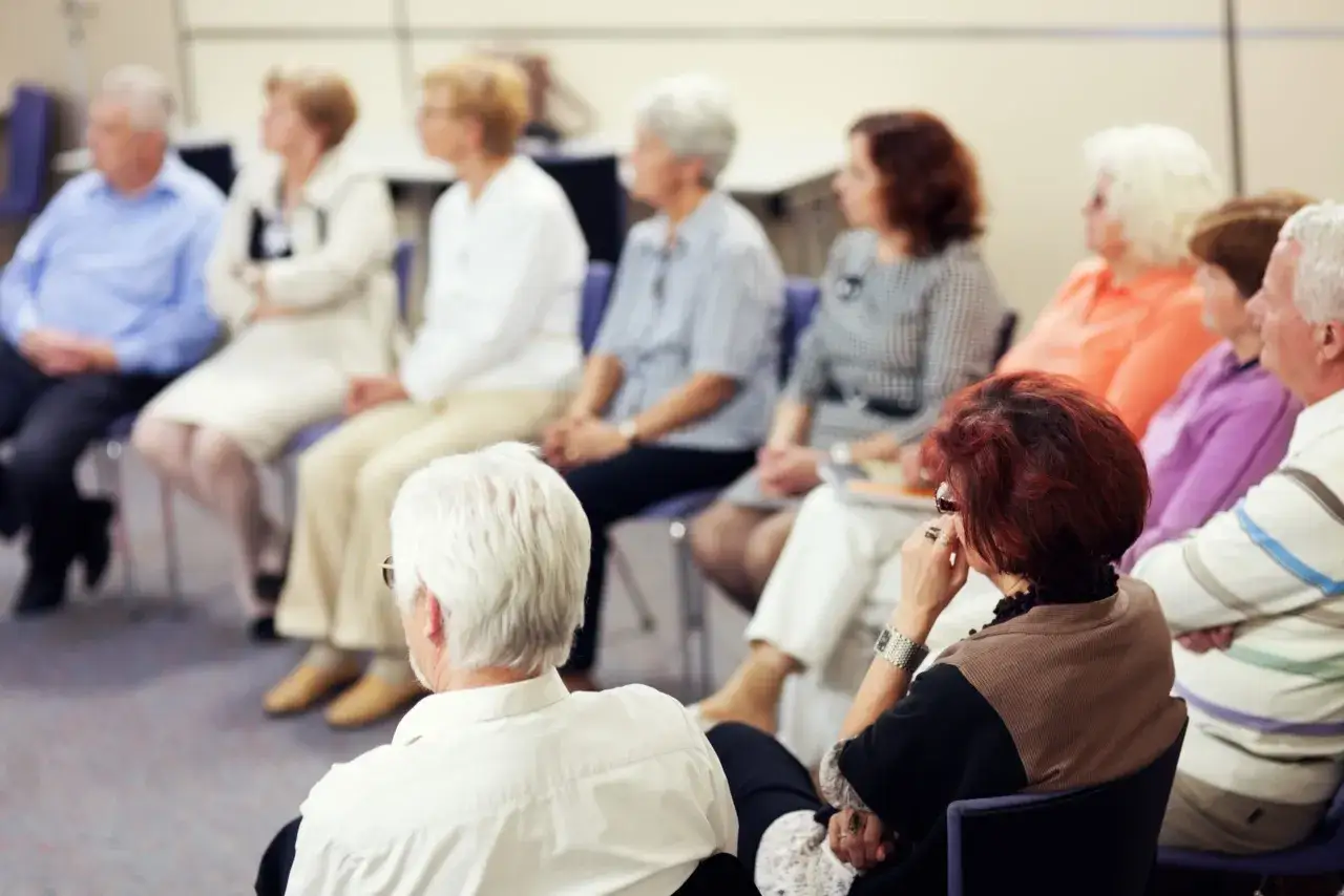 Senioren in einer Gruppe, die über Depressionen im Alter sprechen. Sie sitzen auf Stühlen und hören aufmerksam zu.