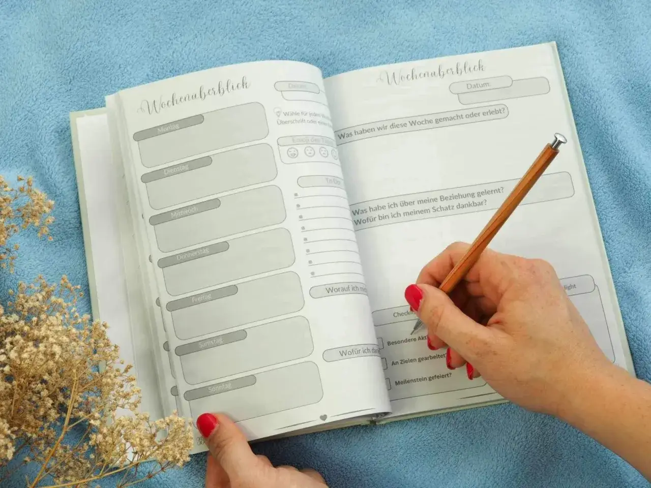 Ein offenes Notizbuch mit Wochenübersicht und Fragen zur Selbstreflexion Beziehung. Eine Hand hält einen Stift und schreibt.