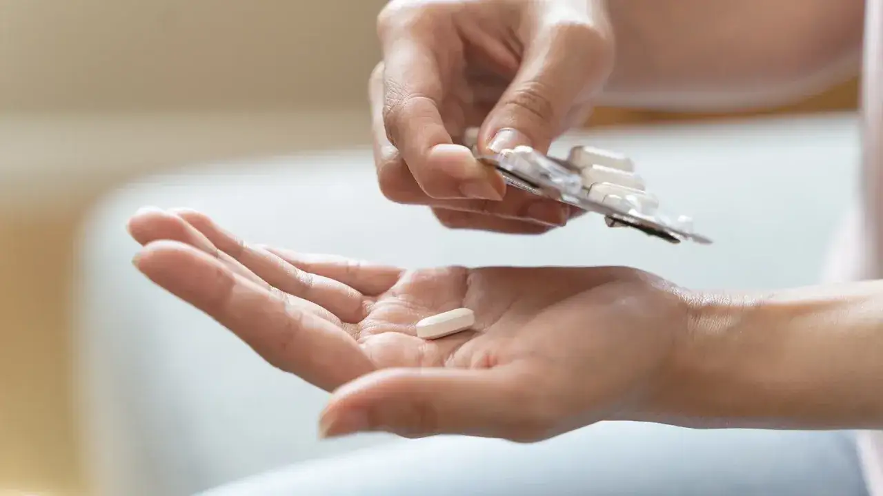 Eine Hand h&auml;lt eine Tablette, w&auml;hrend die andere Hand eine Blisterpackung mit weiteren Pillen h&auml;lt. M&ouml;gliche pregabalin nebenwirkungen im Blick.