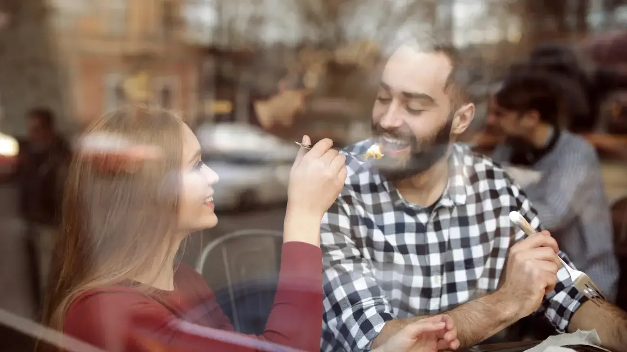 Ein junger Mann findet Freude am Essen, als ihn eine Frau durch ein Fenster f&uuml;ttert.