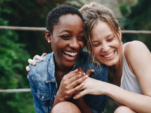 Zwei lachende Frauen, die sich umarmen. Ein Bild, das die psychologische Definition von Freundschaft perfekt einfängt: Vertrauen, Nähe und Freude.