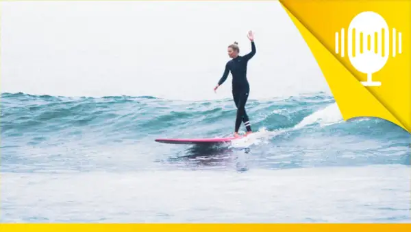 Surferin auf einer rosa Tafel, die mit erhobener Hand über die Wellen gleitet. Ein Symbol für das Lebensfreude wiederfinden.