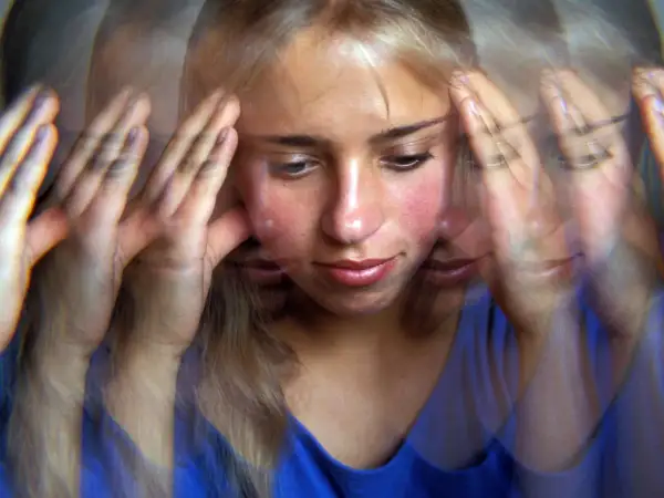 Verzerrte Ansicht einer jungen Frau mit Händen an den Schläfen, die innere Zerrissenheit und psychotische Depression erfahrungsberichte widerspiegelt.