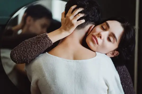 Frau umarmt ihren Partner, der sich abwendet. Sie sucht Nähe, wenn sie sich depressiv fühlt. Was tun?