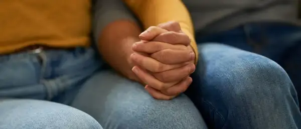 Zwei Hände halten sich fest. Die Frage, warum trennen sich depressive vom Partner, beschäftigt viele.