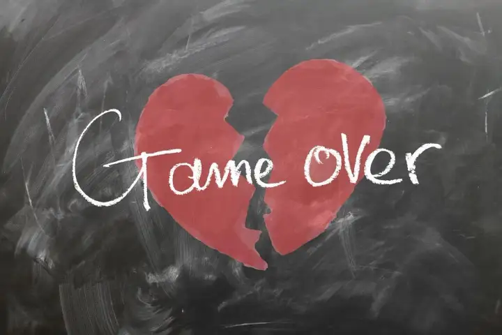 Ein zerbrochenes Herz auf einer Tafel mit der Aufschrift "Game Over". Ein Symbol für den tiefen Schmerz und die Trauer nach einer Trennung.